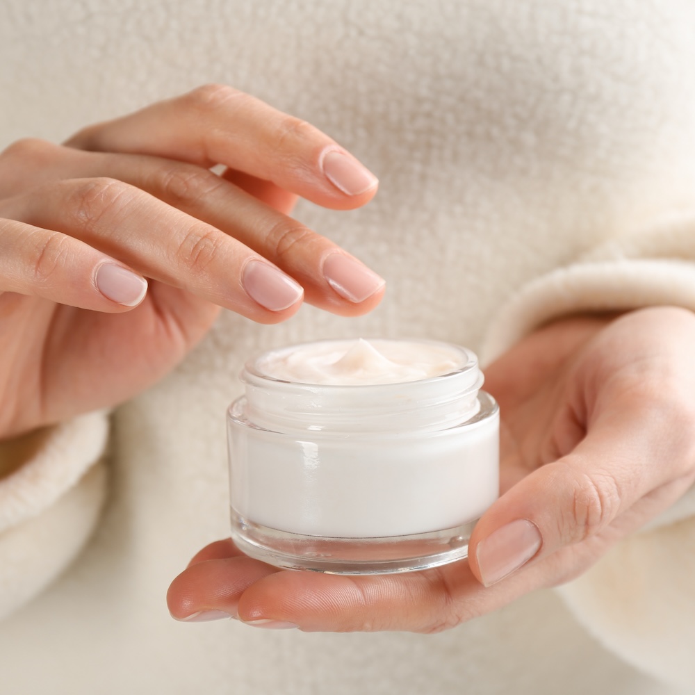 A woman holding a jar meant to evoke a simple skincare routine